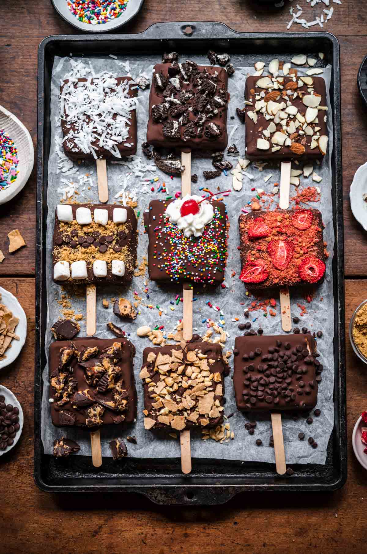 overhead view of vegan ice cream bars with various toppings on a sheet pan. 