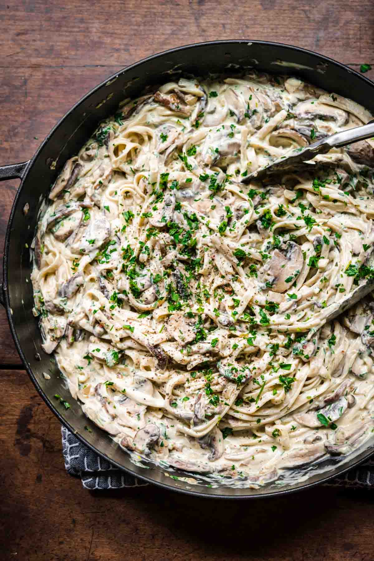 Overhead view of mushroom alfredo in a pot garnished with parsley.
