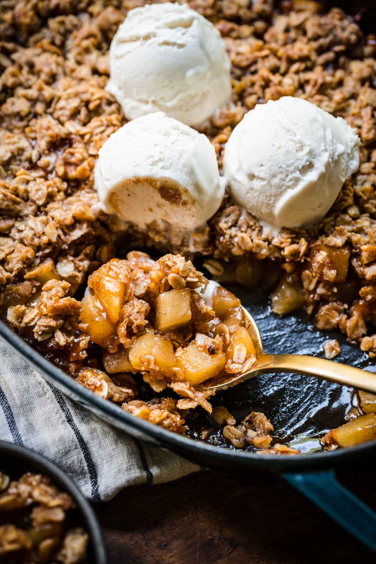 close up view of gluten free apple crisp on serving spoon in skillet. 