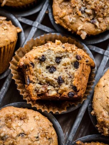 Banana walnut muffin in a muffin tin with a bite taken out.