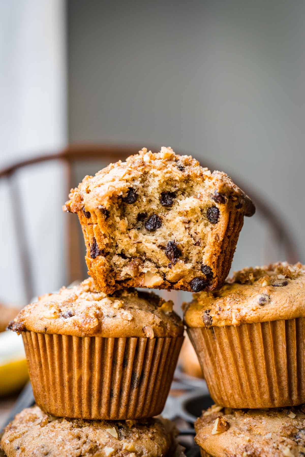 Banana muffins stacked on top of one another, one with a biten taken out of it.