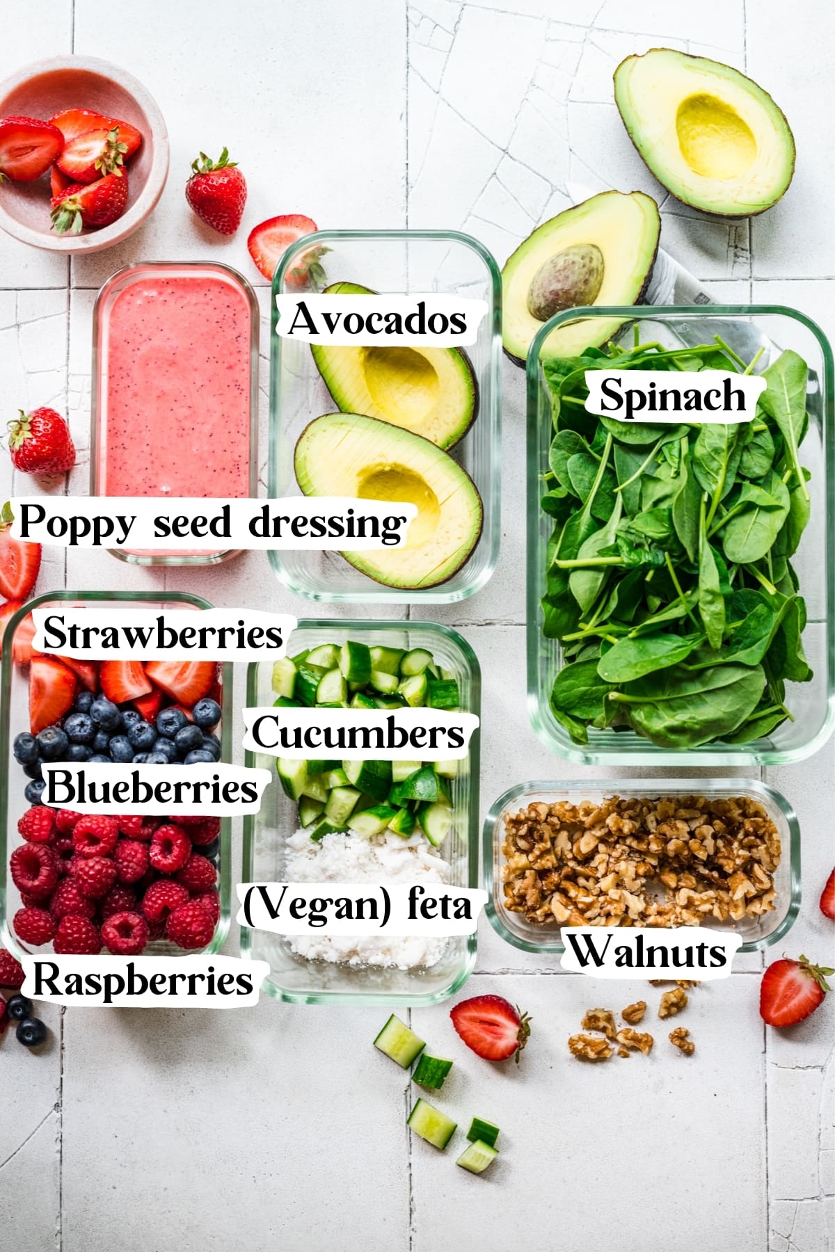 overhead view of ingredients for berry avocado salad in separate tupperware containers. 