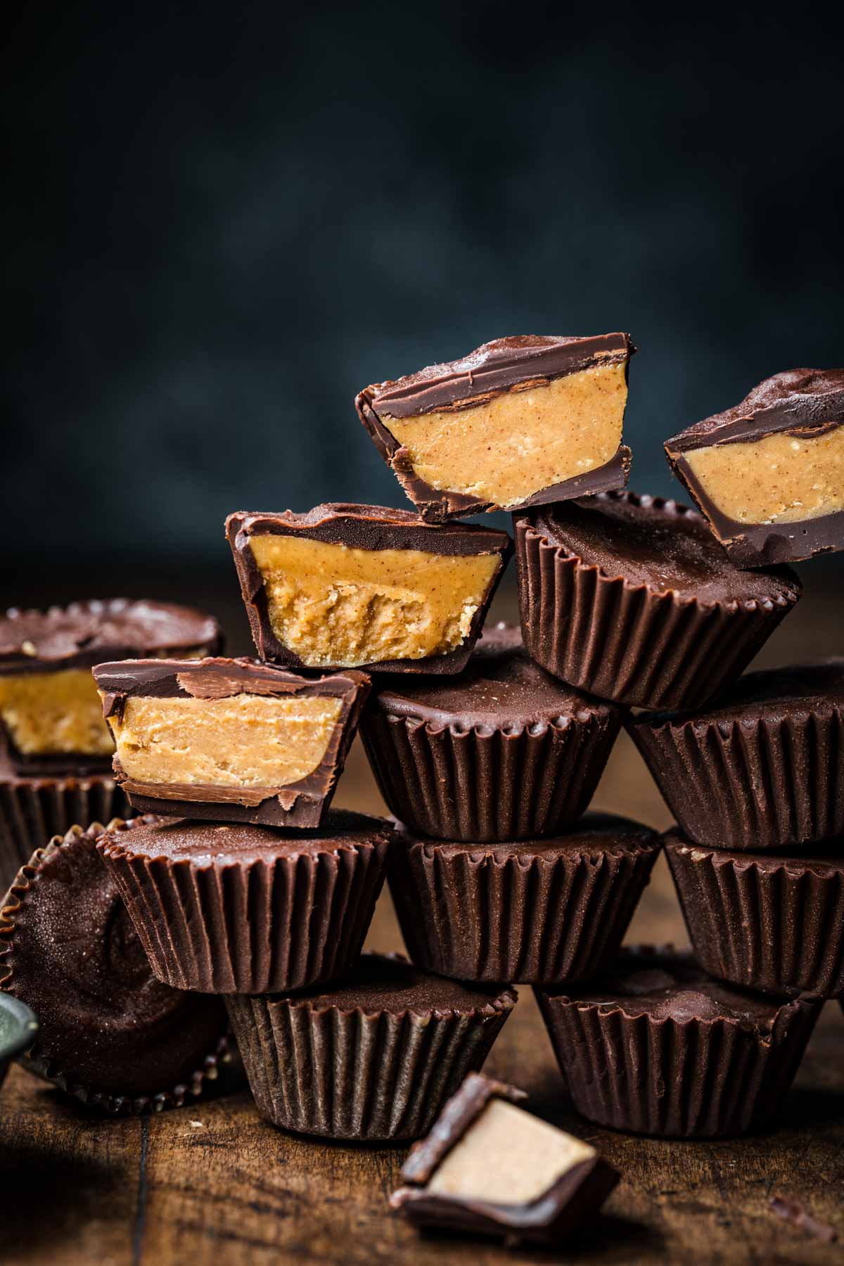 side view of a stack of homemade vegan peanut butter cups with some sliced in half and some whole. 