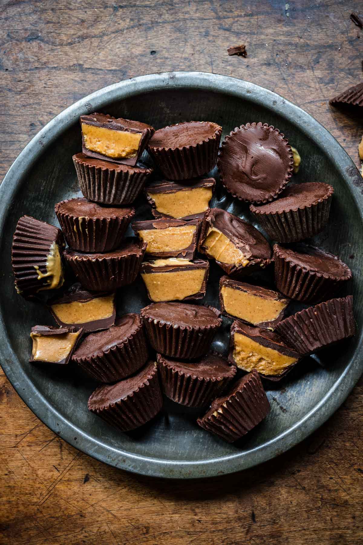 overhead view of vegan peanut butter cups on tin tray with some sliced in half and some whole. 