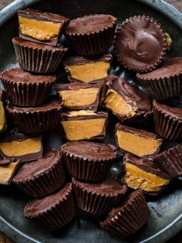 overhead view of vegan peanut butter cups on tin tray with some sliced in half and some whole.
