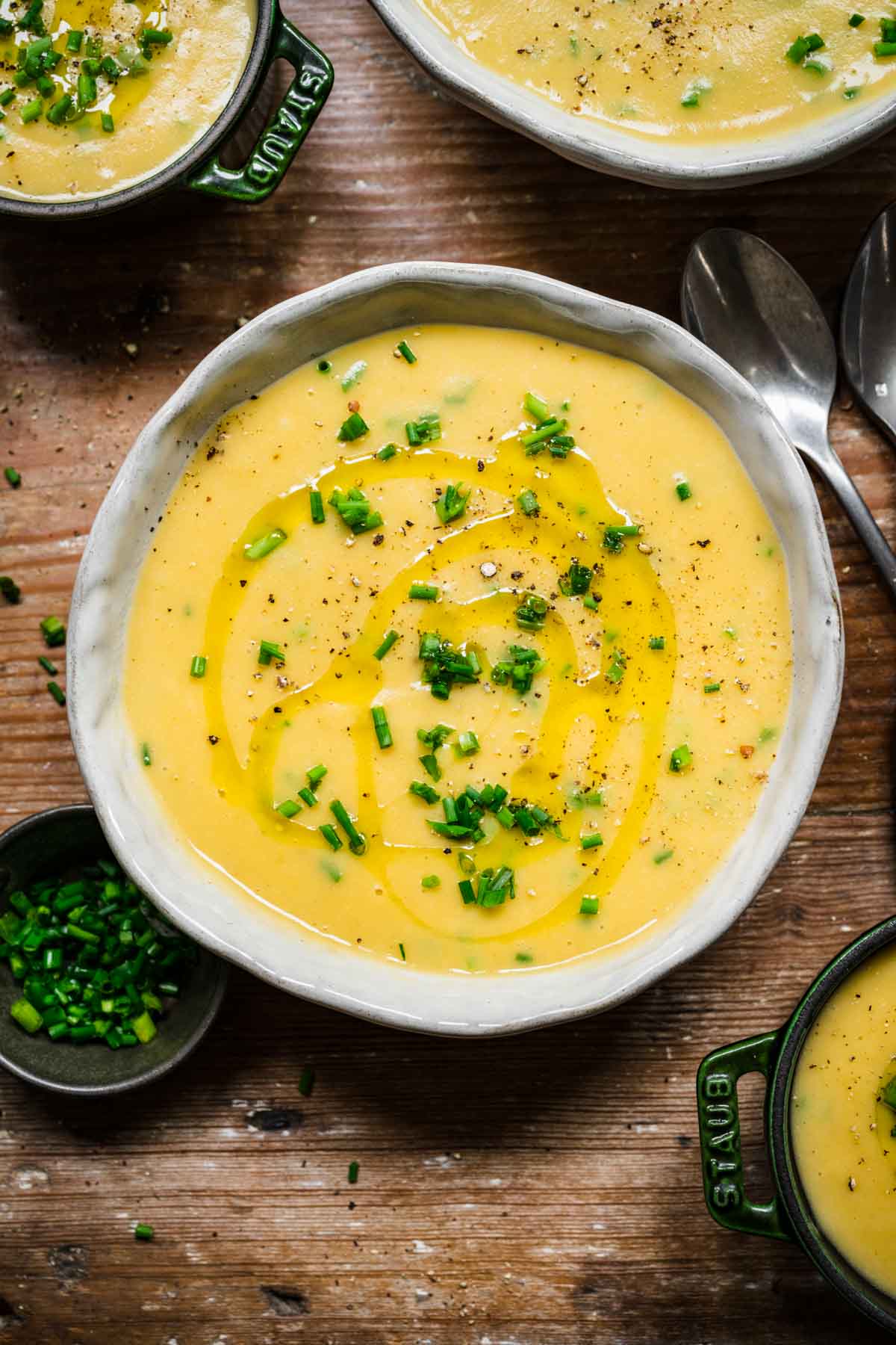 Overhead view of potato leek soup in a bowl garnished with chives, oil, and pepper.