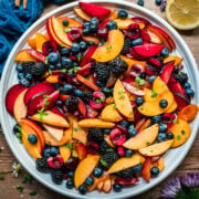 overhead view of summer fruit salad with stone fruit and berries on large white platter.