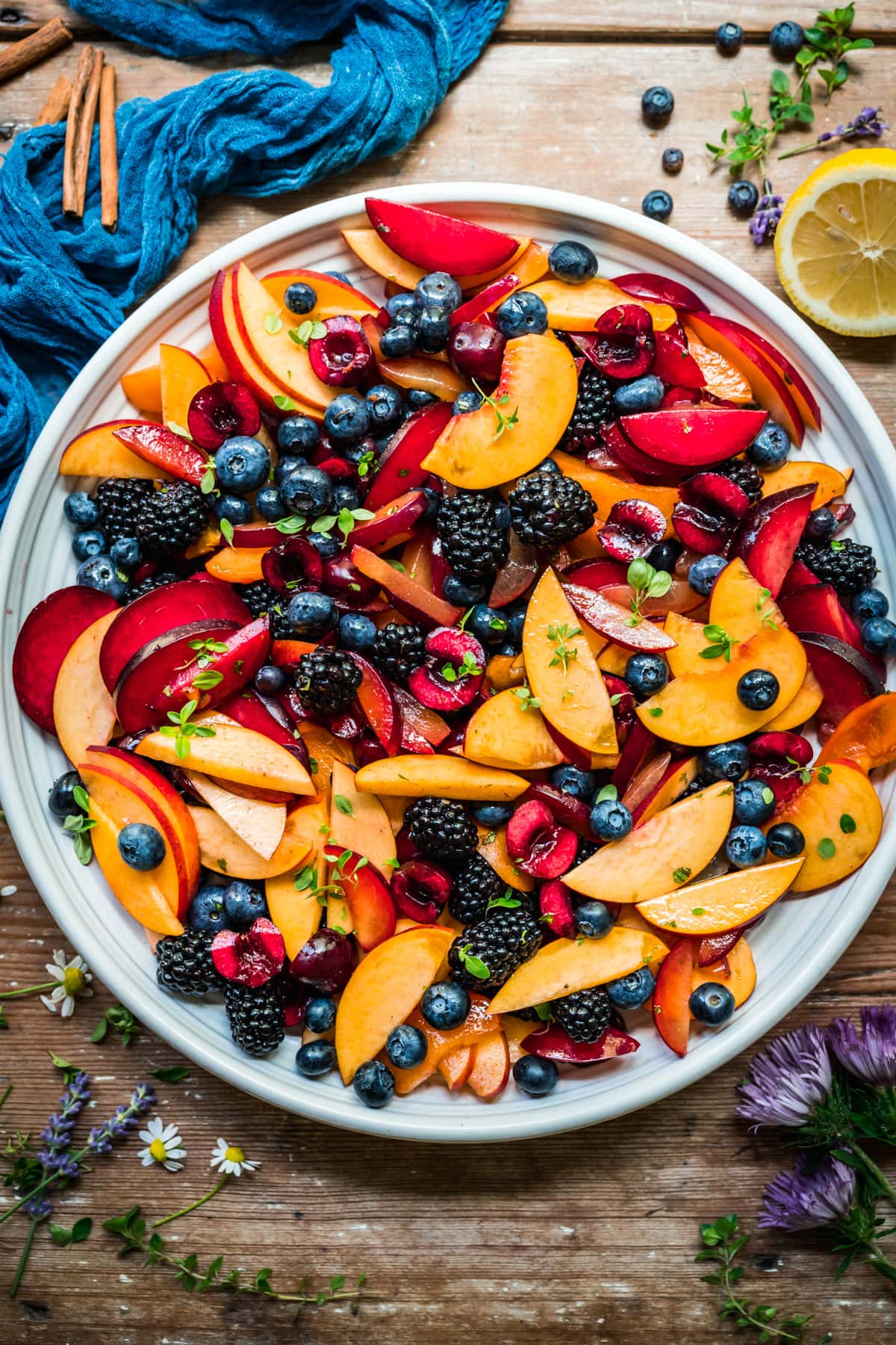 overhead view of summer fruit salad with stone fruit and berries on large white platter. 