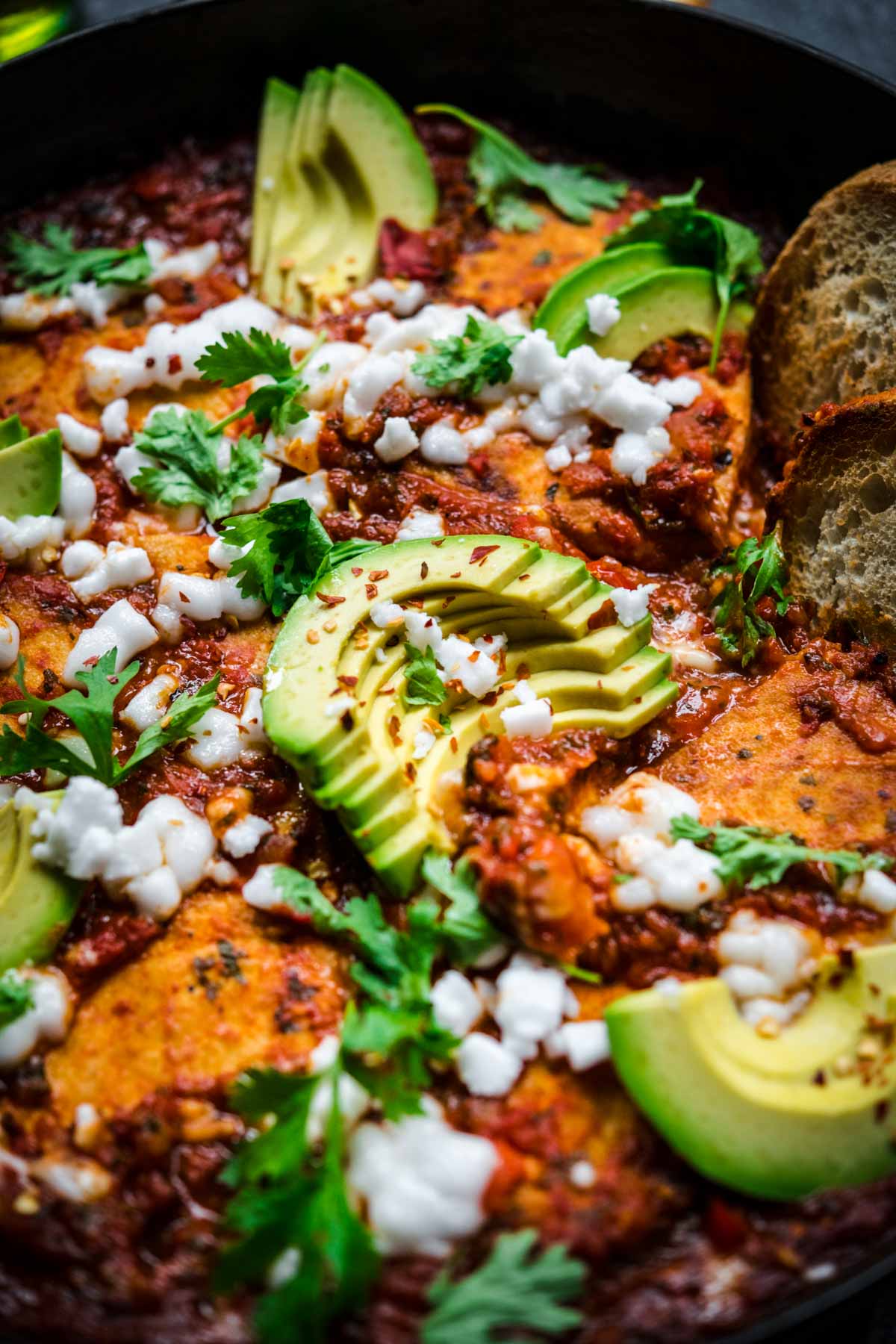 Close up of shakshuka focusing on a sliced avocado for garnish.