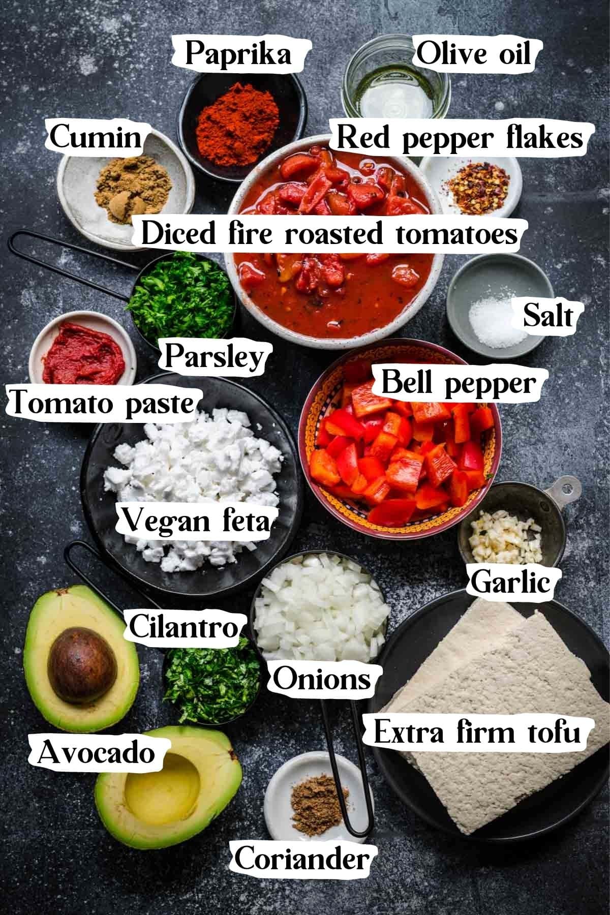 Overhead view of vegan shakshuka ingredients, including tofu, spices, avocado, and feta.