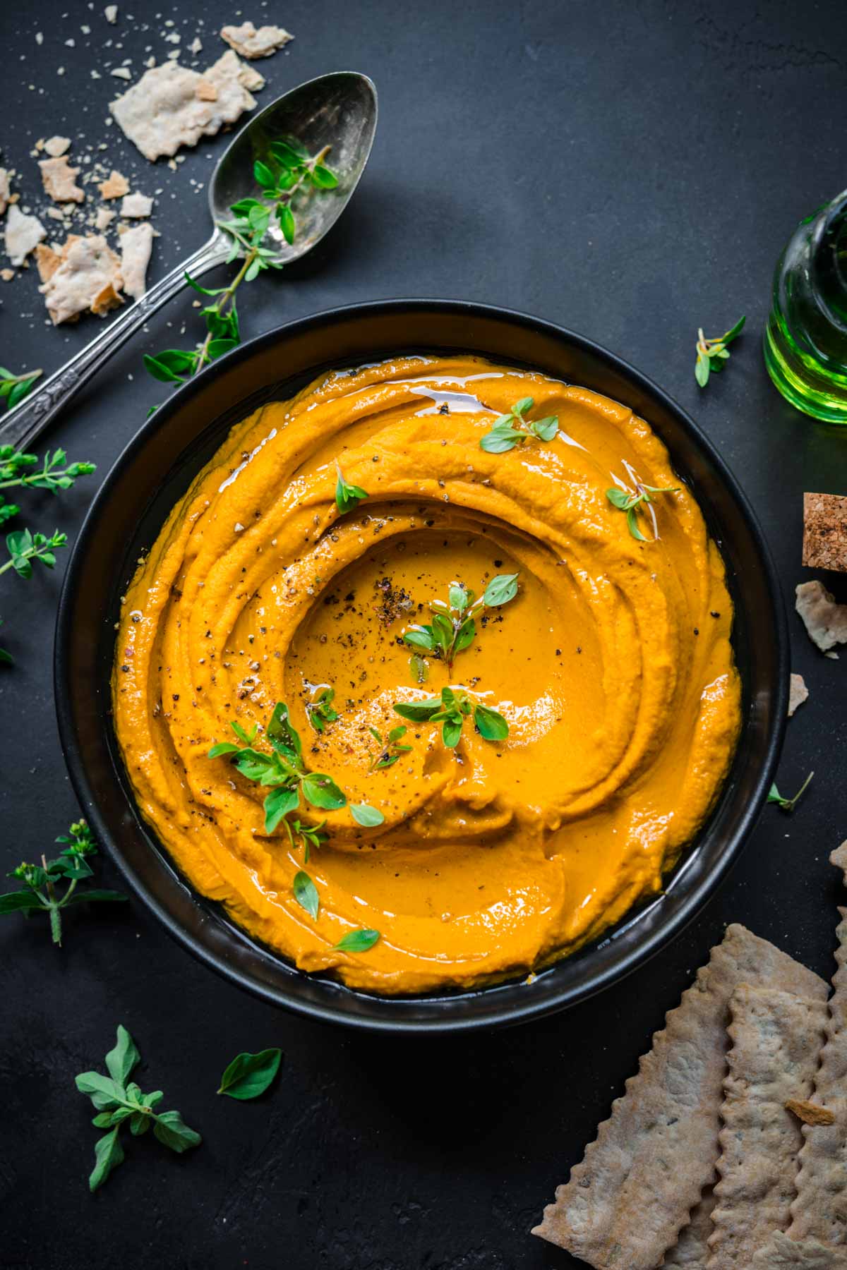 Roasted carrot dip in a bowl seen from above garnished with olive oil and herbs.