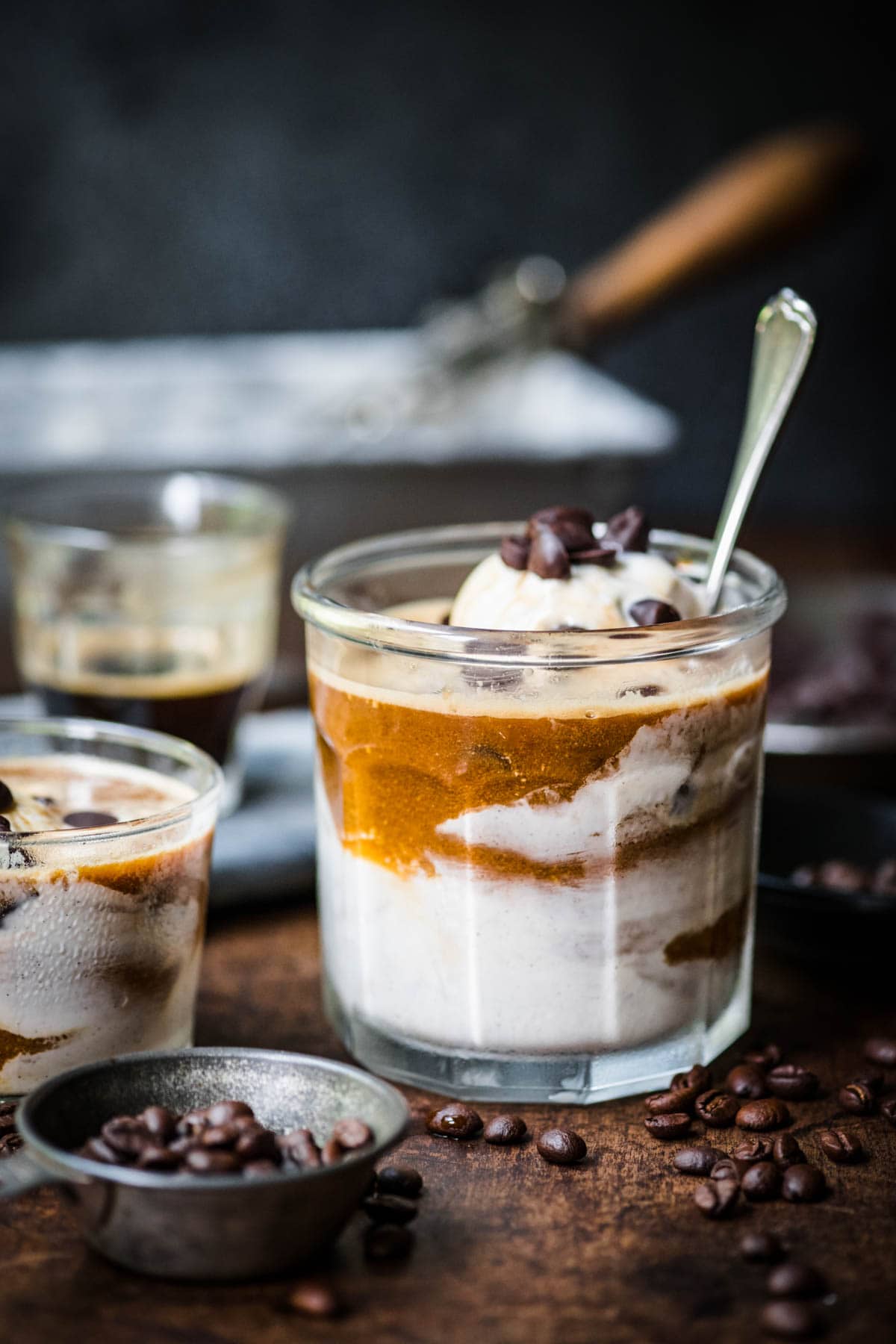 Front view of affogato in a glass cup with a spoon inside it.