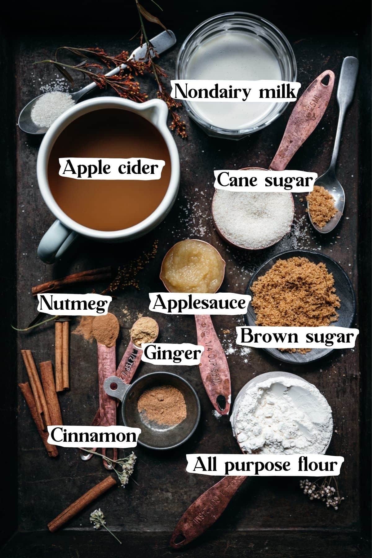 Overhead view of key apple cider donut ingredients, including apple cider, applesauce, sugar, and cinnamon.