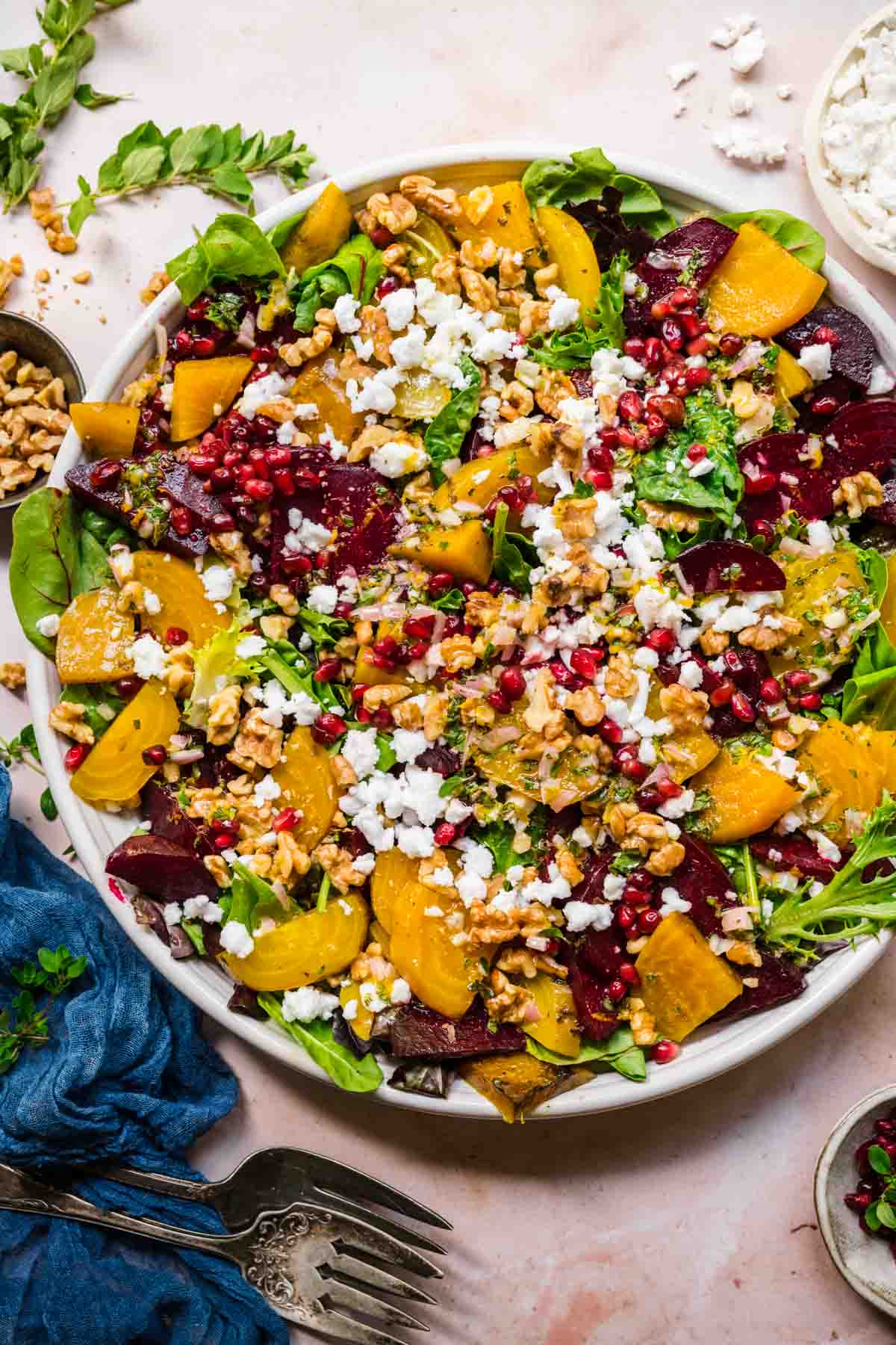 Overhead view of beet feta salad with walnuts and pomegranate on a white serving platter. 