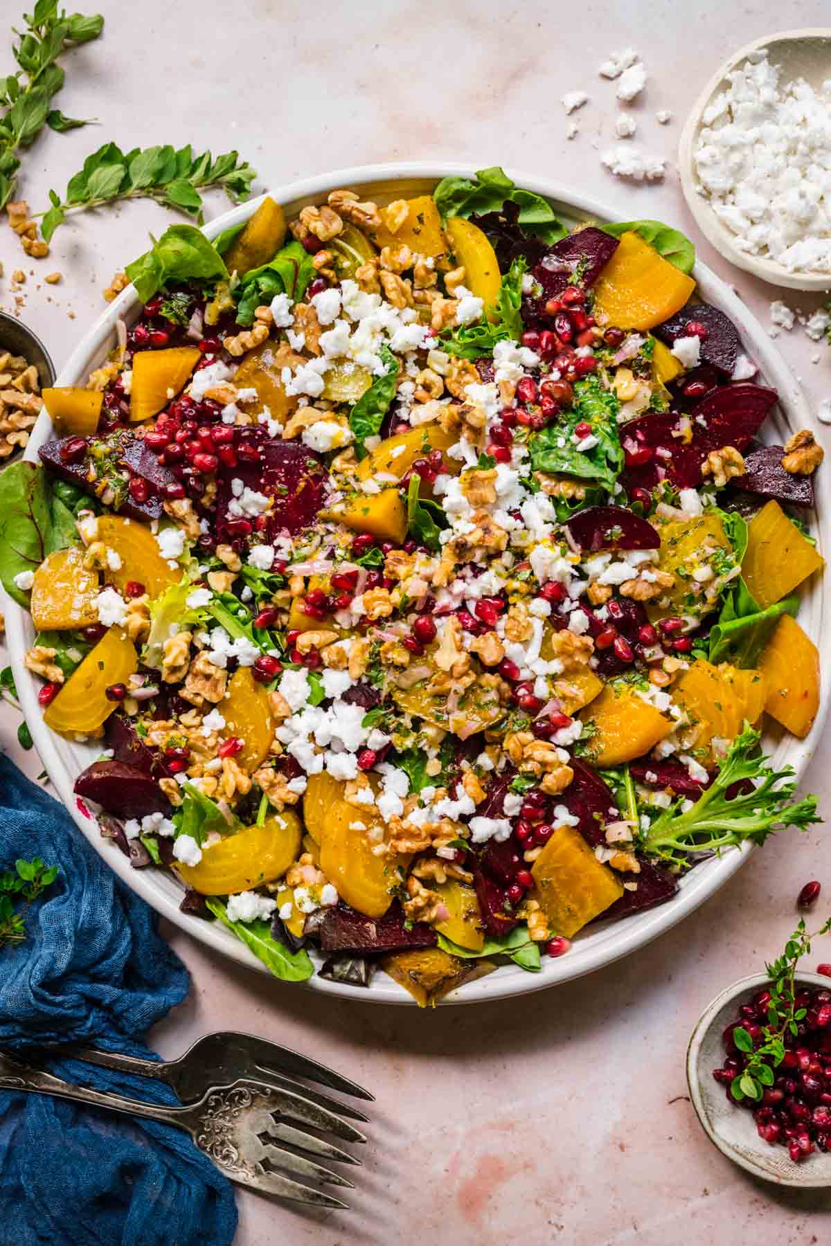 Overhead view of beet feta salad with walnuts and pomegranate on a white serving platter. 