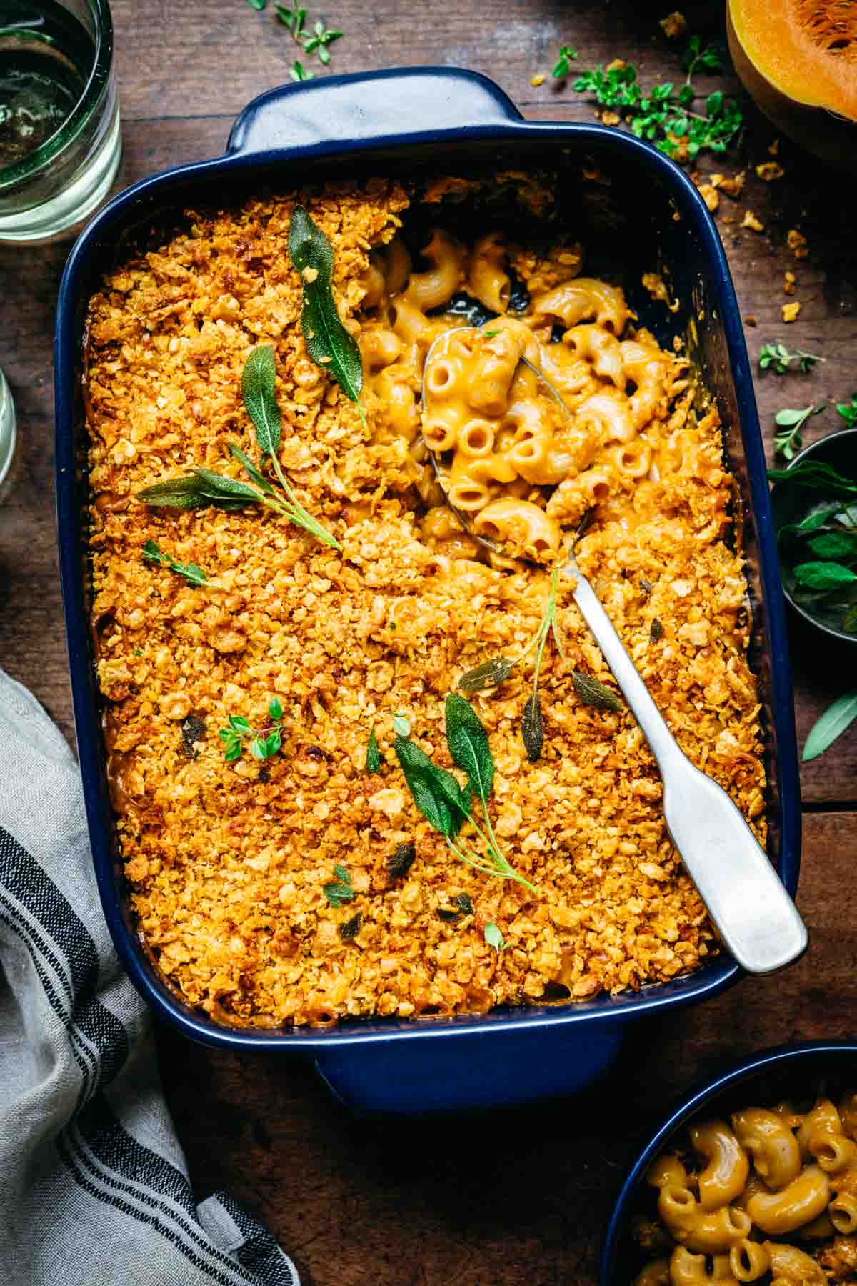 overhead view of vegan butternut squash mac and cheese with breadcrumbs in baking pan with crispy sage on top.