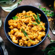 Overhead view of butternut squash mac and cheese in a blue bowl garnished with sage.