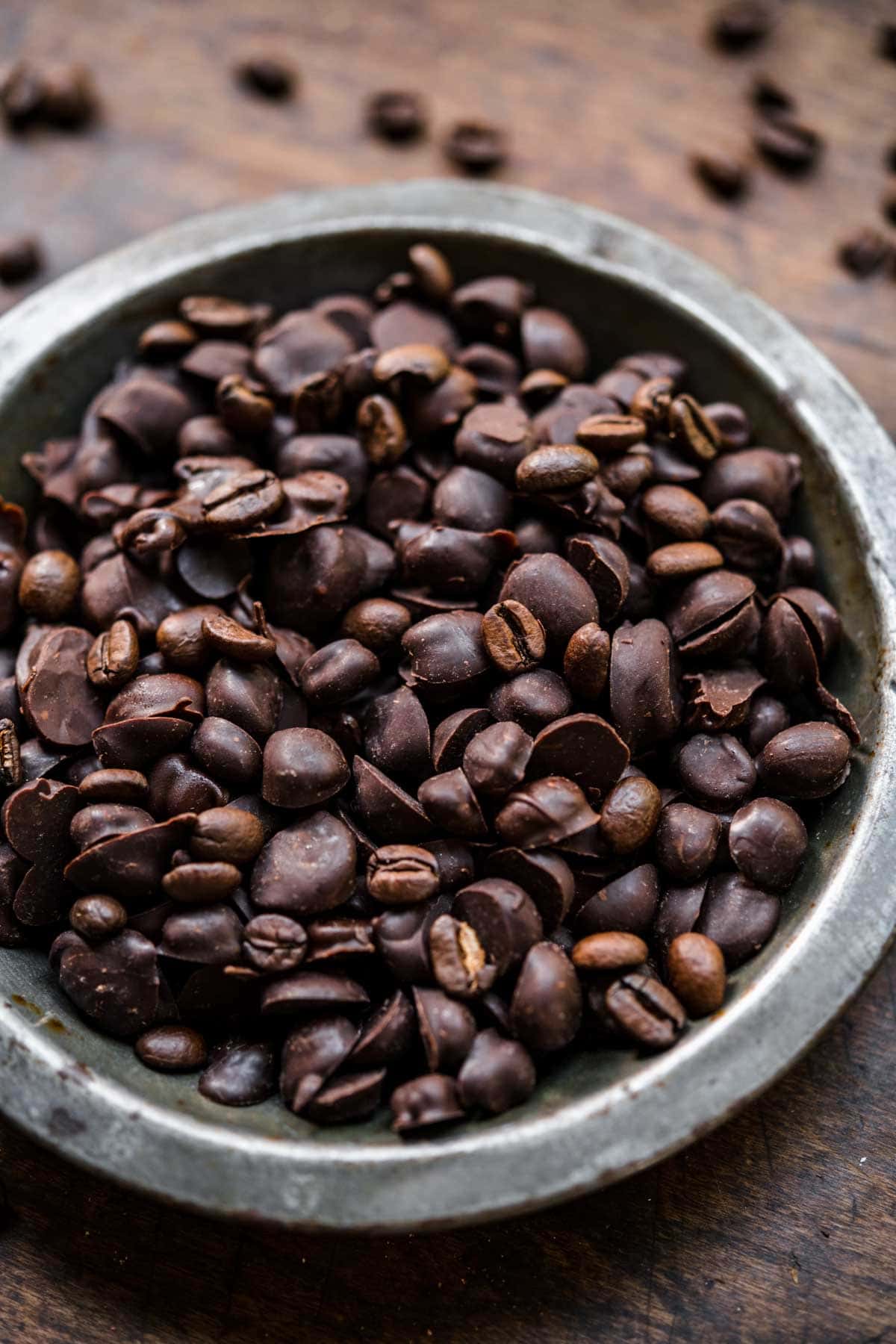 Chocolate covered espresso beans in a bowl seen from above.