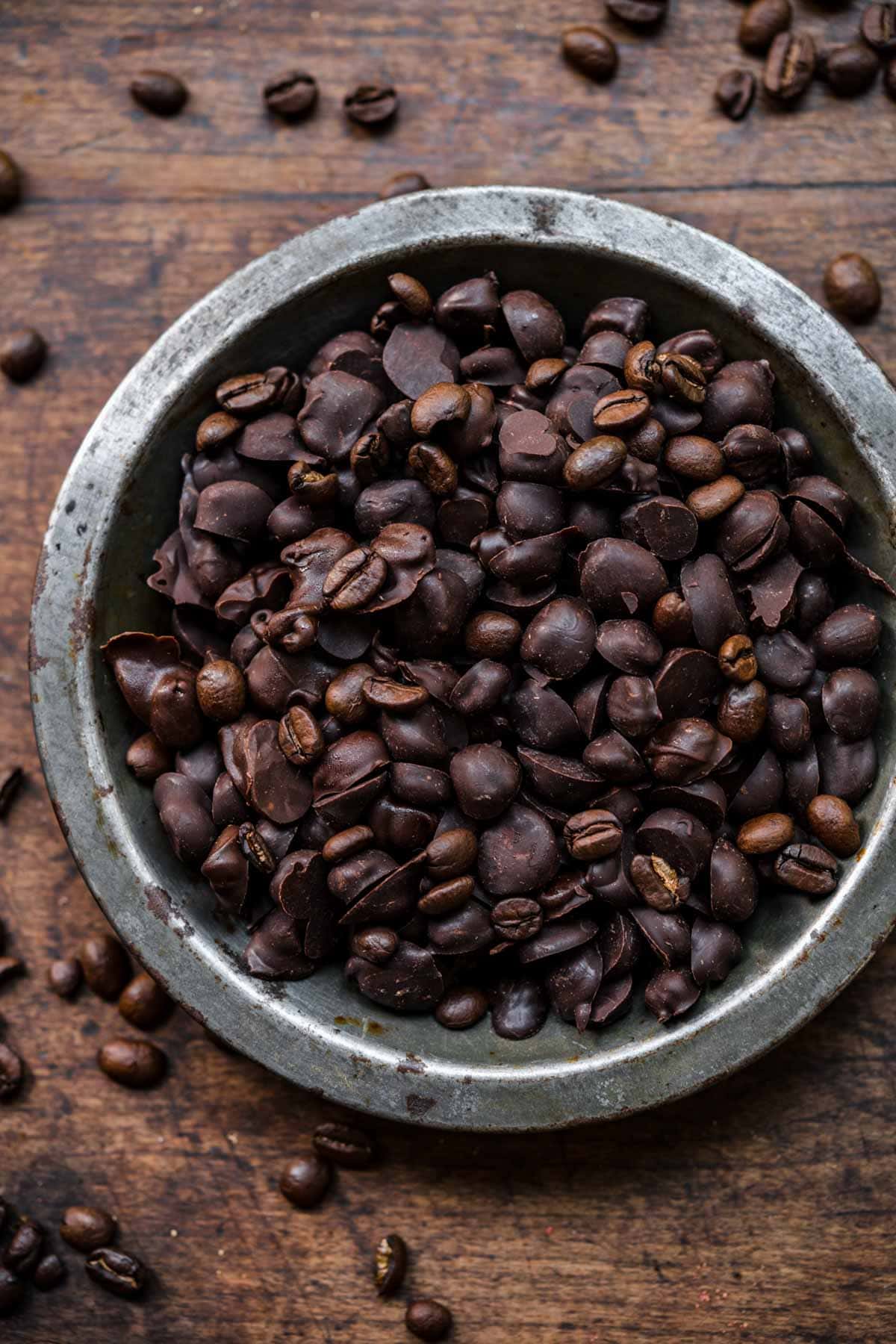 Chocolate covered espresso beans in a bowl seen from above.