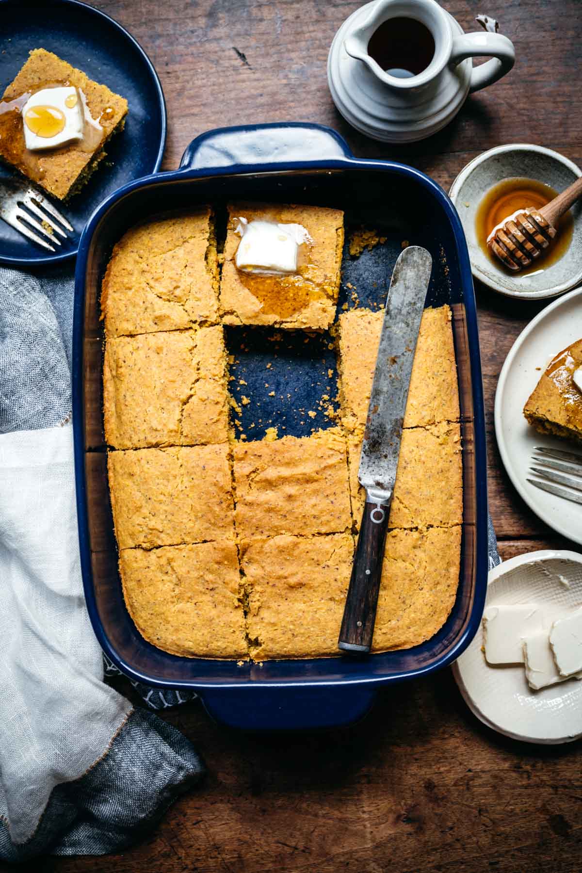 overhead view of sliced vegan cornbread in blue baking dish with knife. 