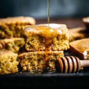 close up view of stack of gluten free vegan cornbread with drizzle of maple syrup.