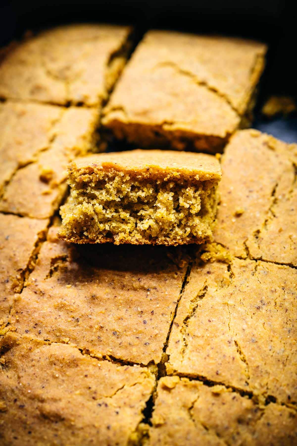 close up view of slice of gluten free vegan cornbread in baking dish. 