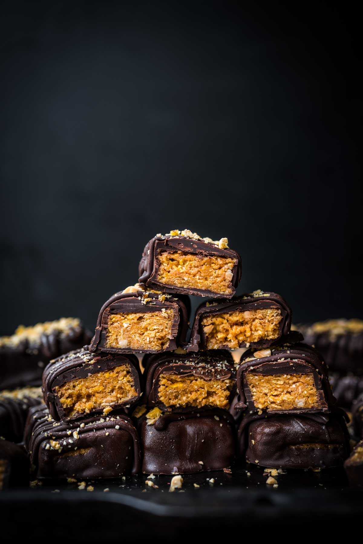 stack of vegan butterfingers cut in half on black backdrop.