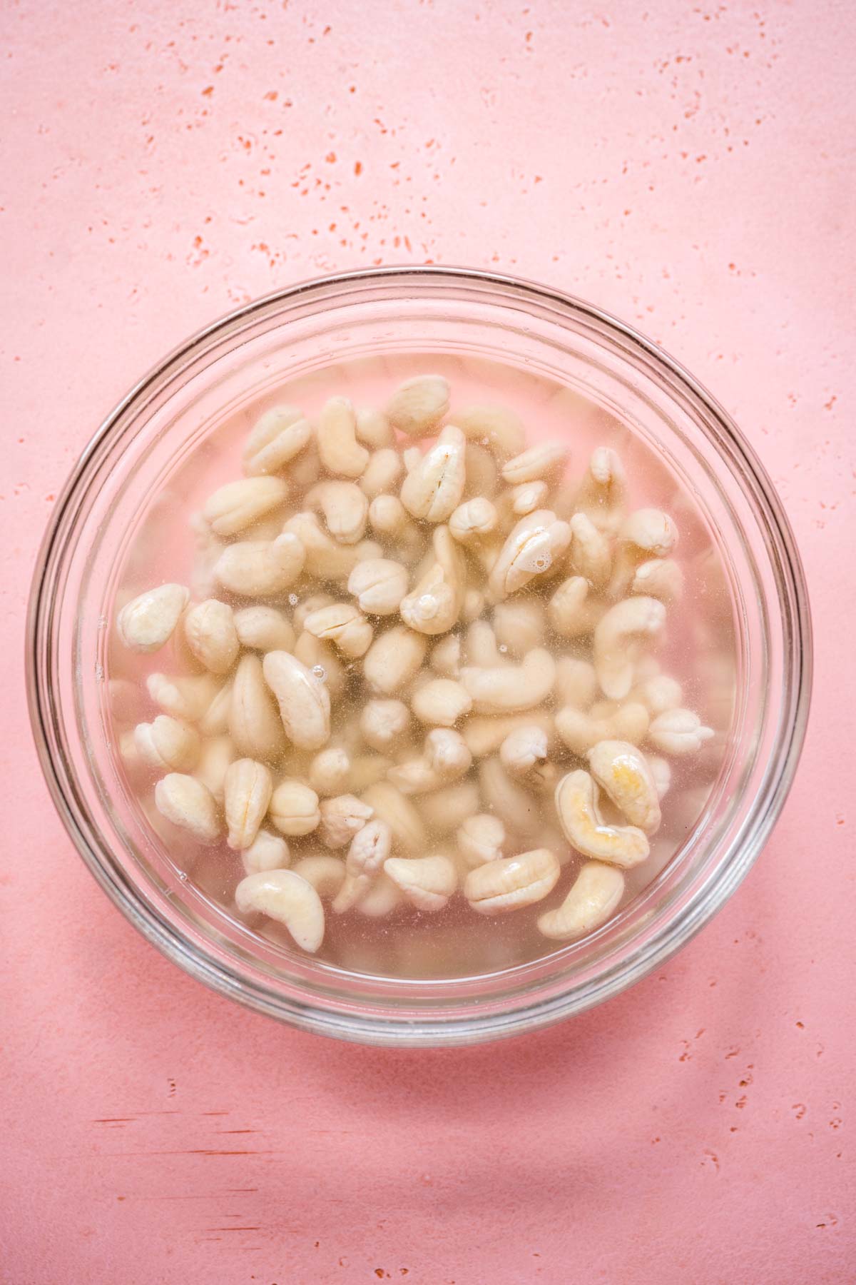 overhead view of cashews soaking in a bowl full of water.