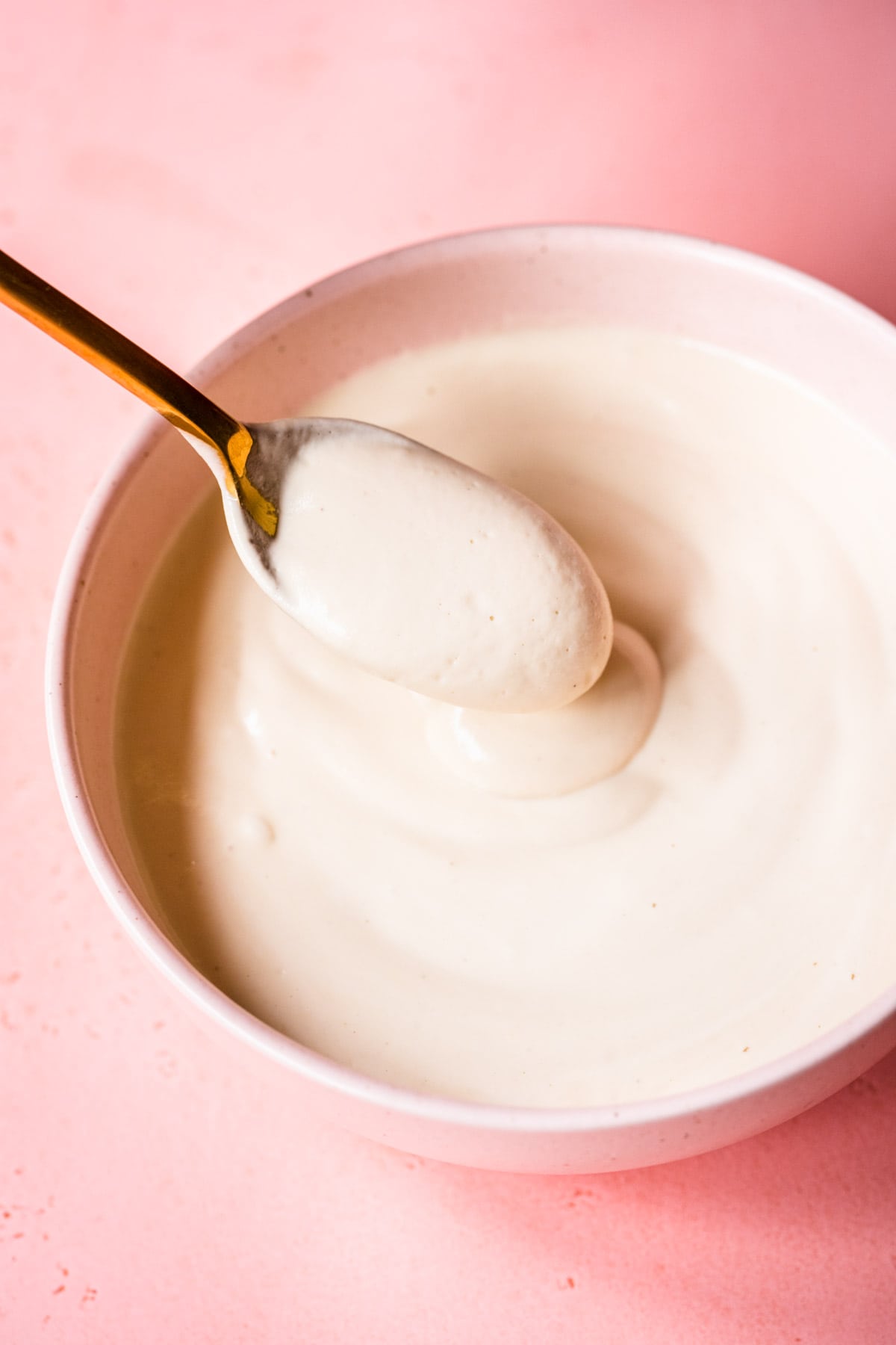 close up view of vegan sour cream in a bowl with spoon.