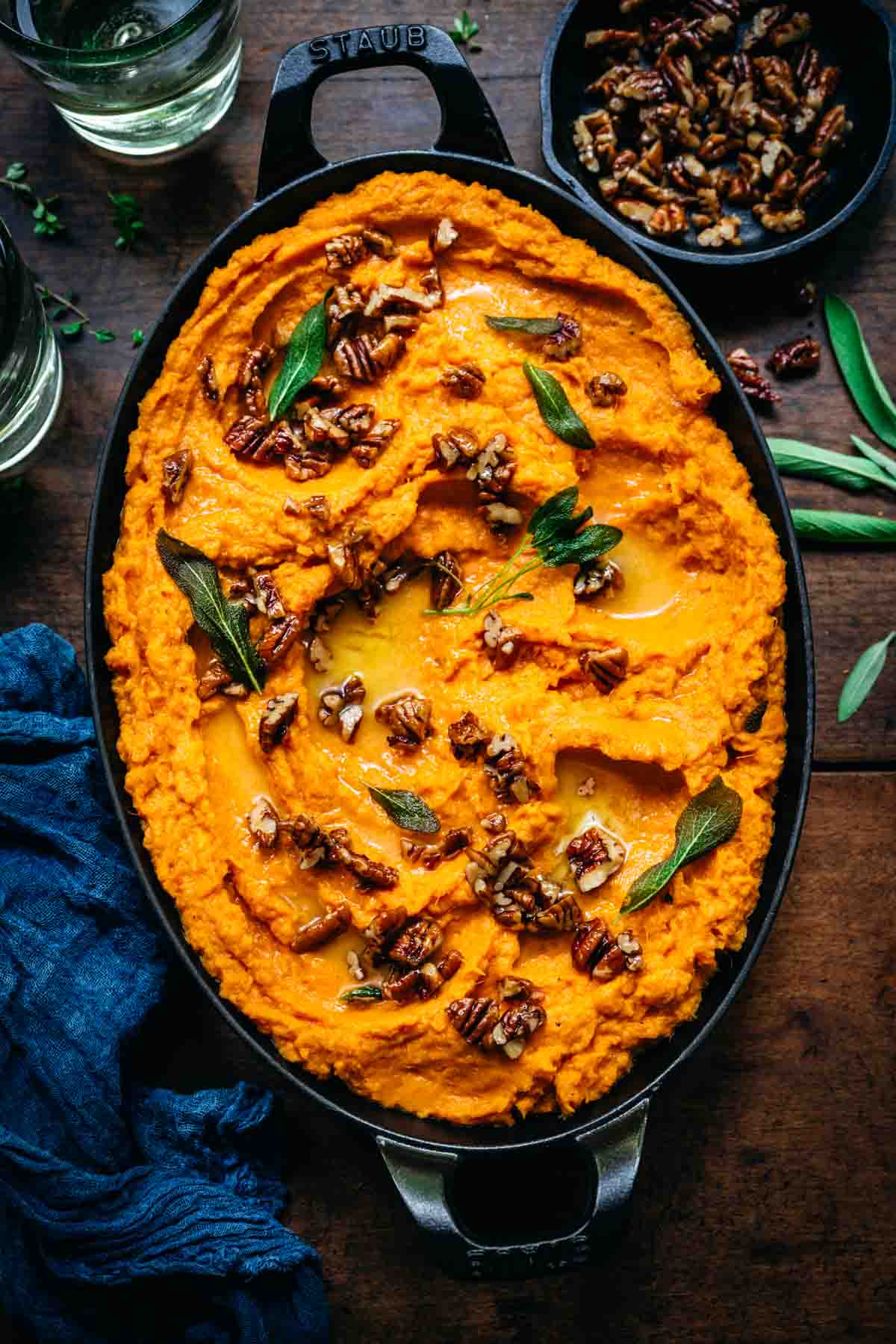 Overhead view of mashed sweet potatoes with pecans and herbs.