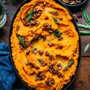 Overhead view of mashed sweet potatoes garnished with nuts and herbs.