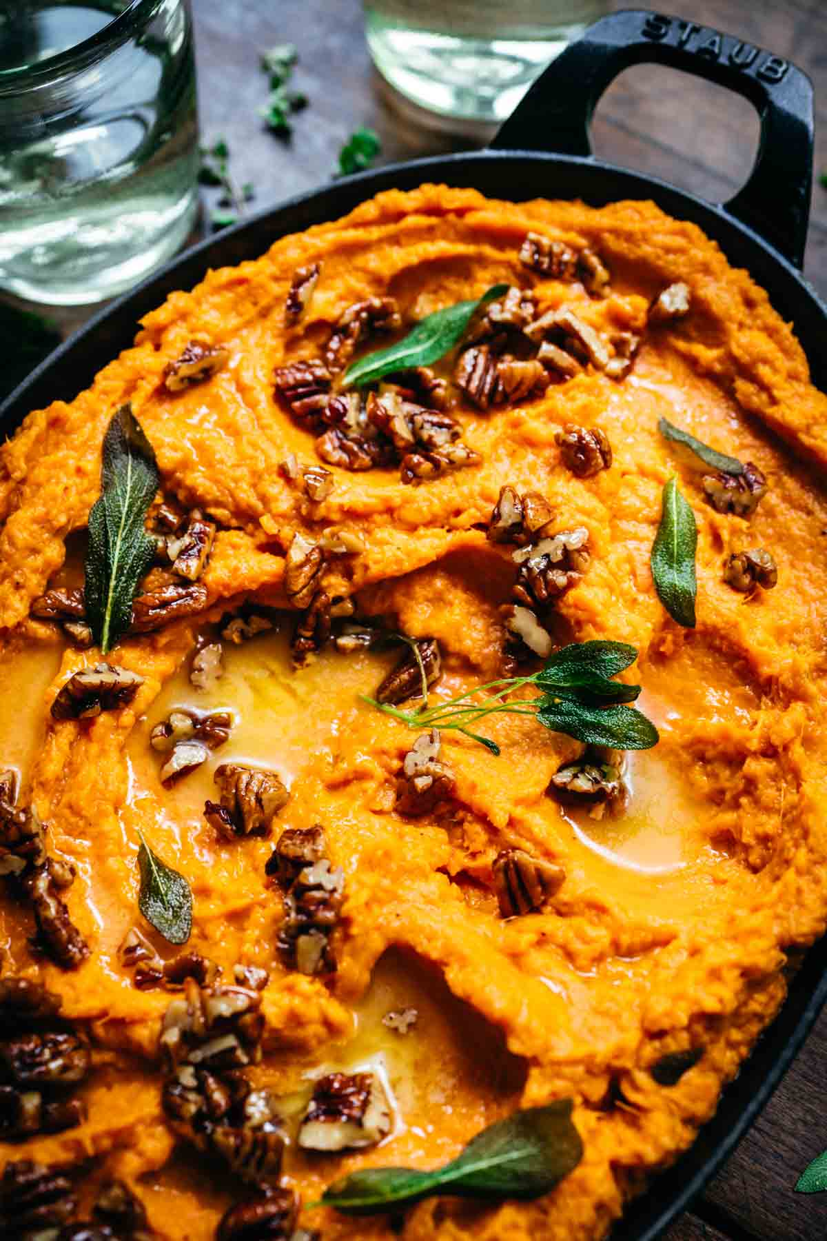 Close up shot of mashed sweet potatoes with pecans and herbs.
