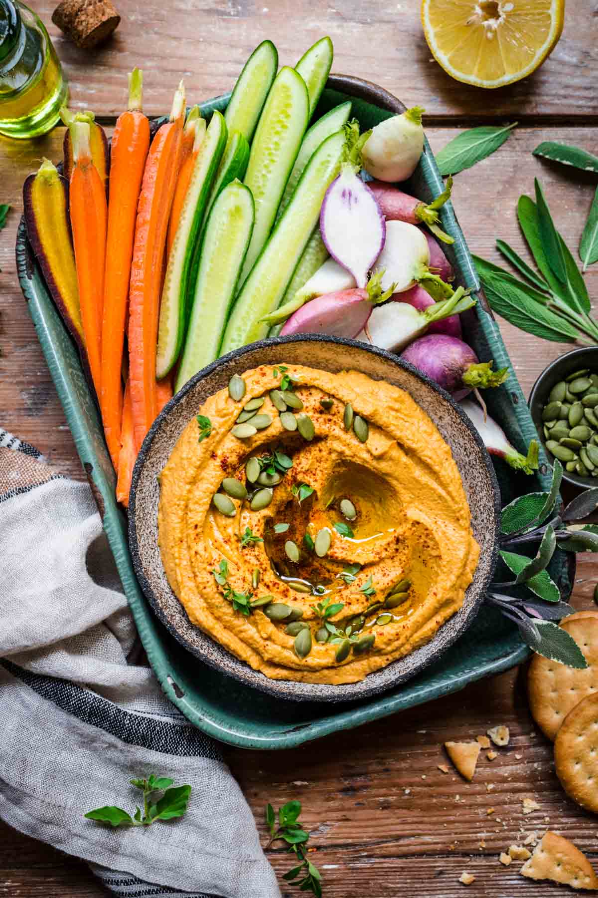 Overhead view of pumpkin hummus on a tray with cut fresh veggies.