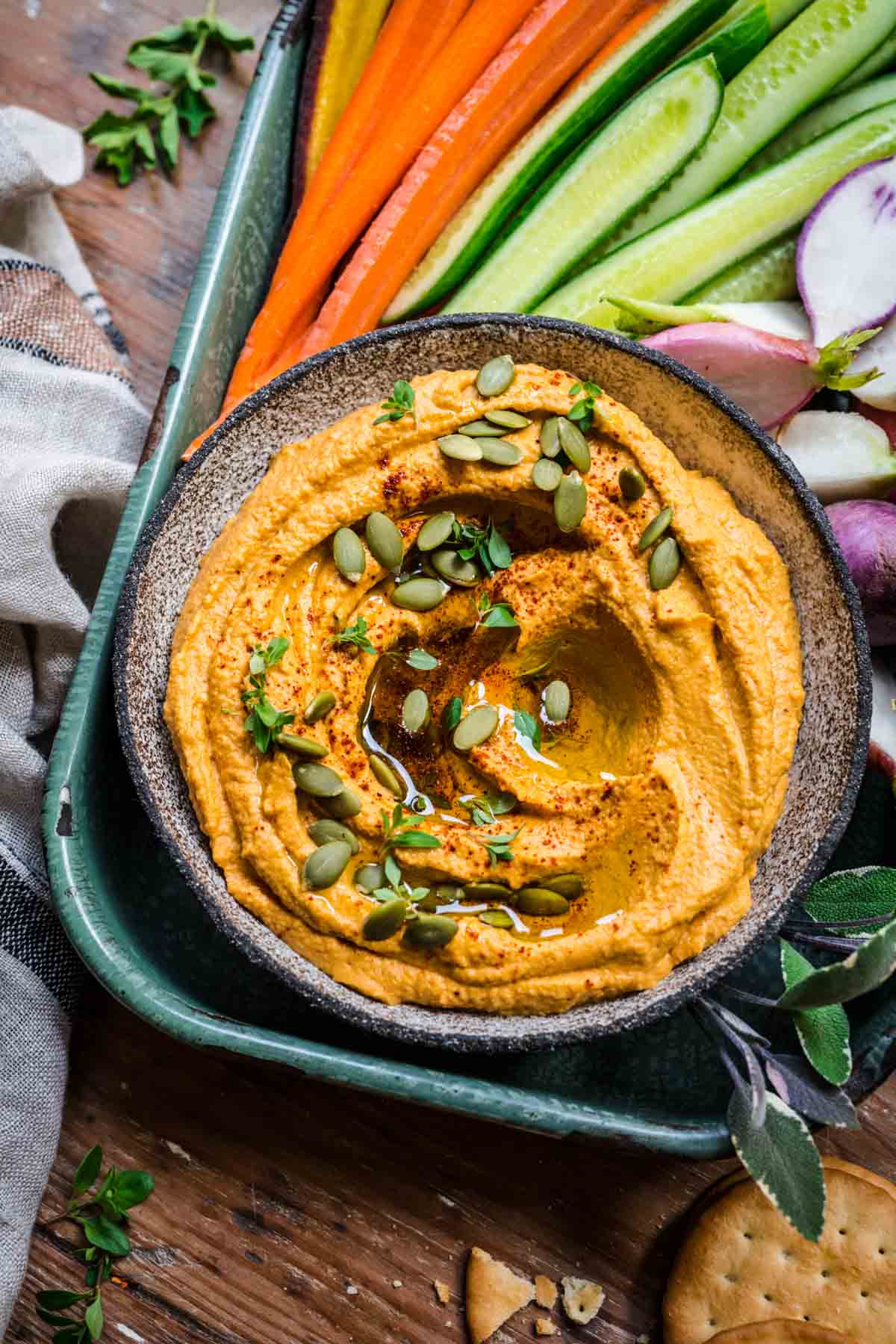 Overhead view of pumpkin sage hummus with pumpkin seeds and fresh cut veggies.