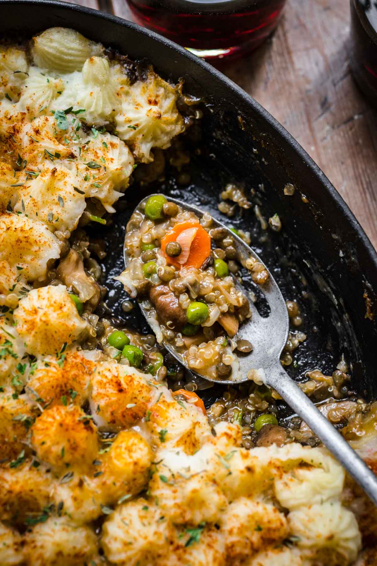 close up view of vegan lentil shepherd's pie filling on serving spoon in skillet. 