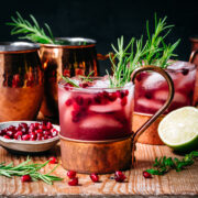 side view of pomegranate moscow mule in copper cocktail glass on wood table.