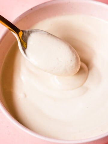 close up view of vegan sour cream in a bowl with spoon.