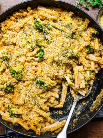 overhead view of vegan broccoli mac and cheese with crispy breadcrumb topping in large skillet.