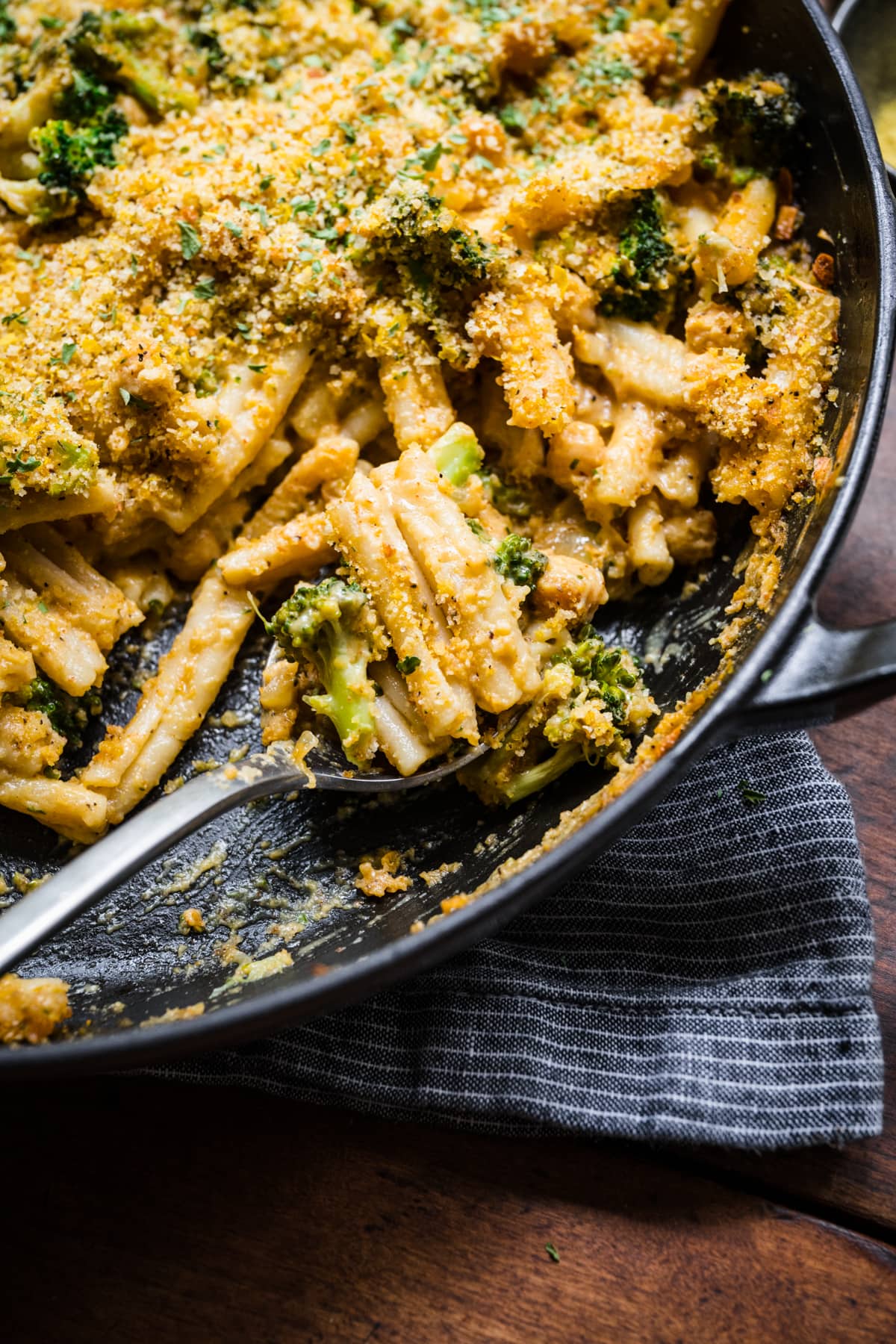 close up view of vegan broccoli mac and cheese with crispy breadcrumb topping in large skillet.