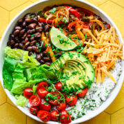 Close up of finished fajita bowl with yellow background.