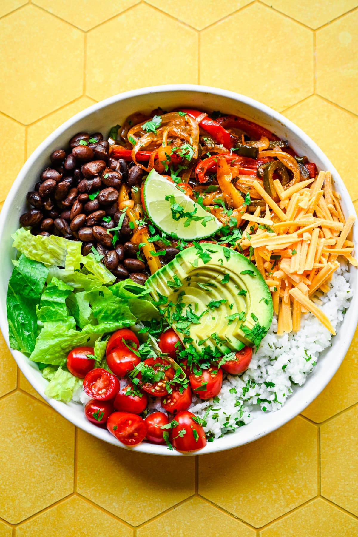 Finished fajita veggies in a bowl with yellow background.