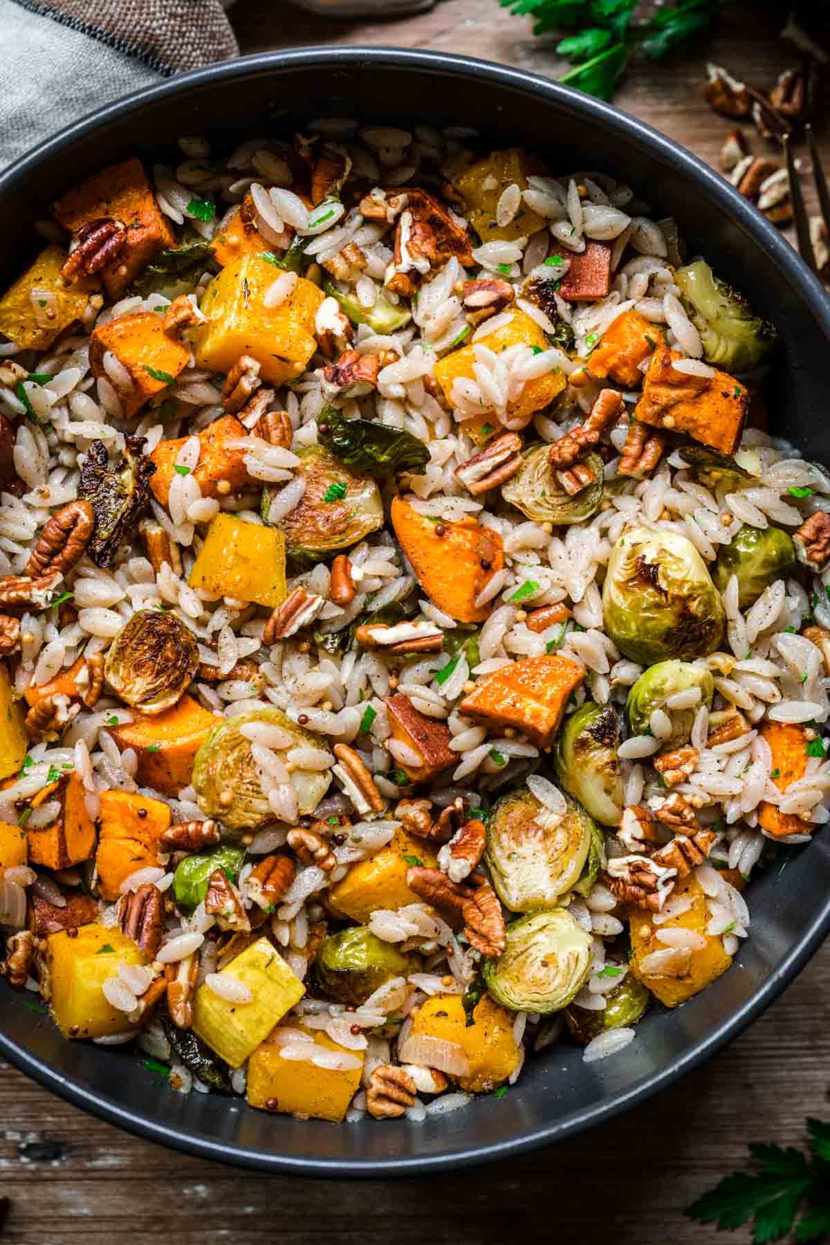 Close up shot of salad in a bowl with brussels sprouts, sweet potatoes, and pecans.