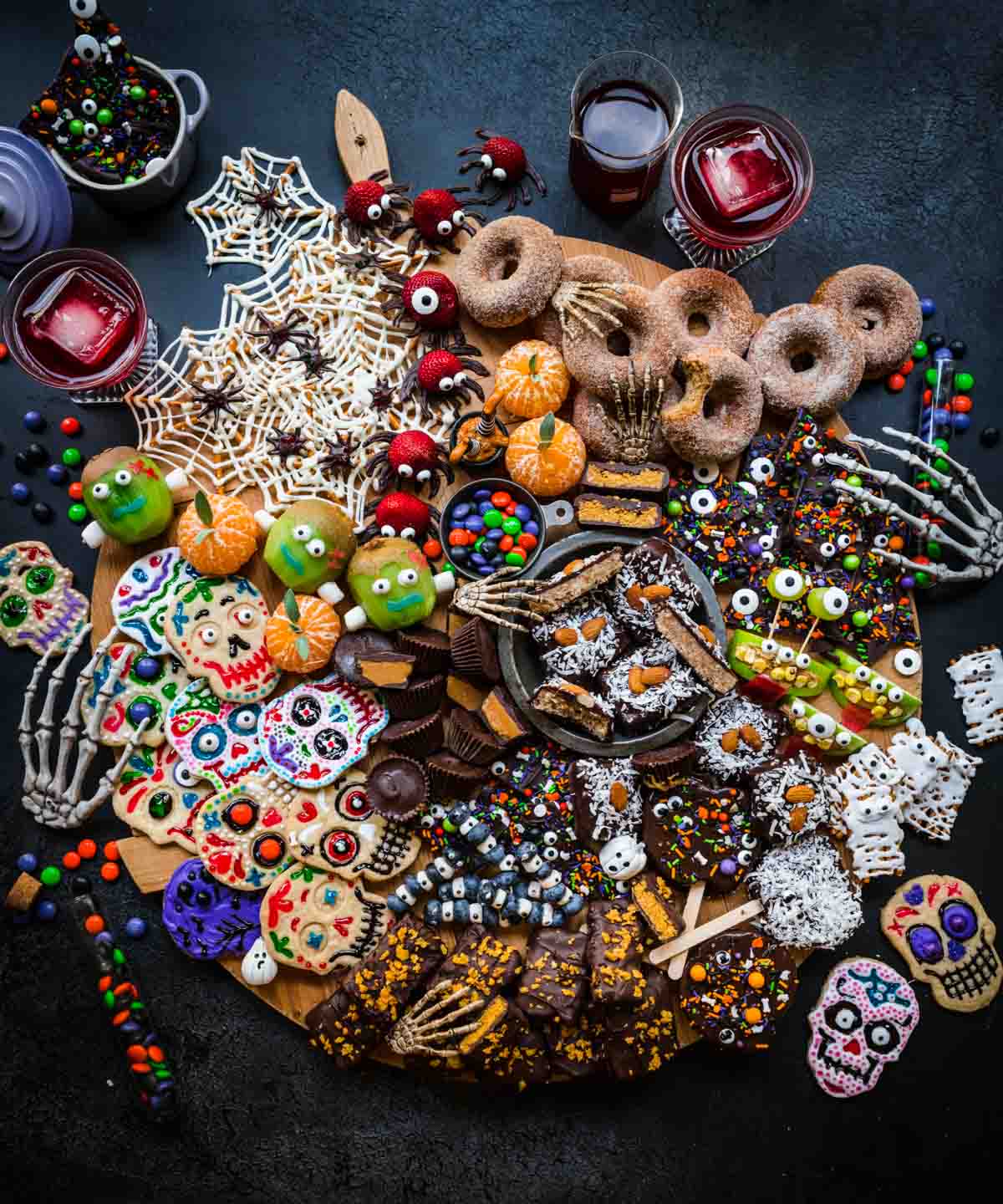 overhead view of halloween dessert charcuterie board with homemade halloween candy, donuts, spooky snacks and more.