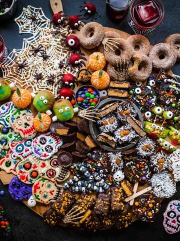 overhead view of halloween dessert charcuterie board with homemade halloween candy, donuts, spooky snacks and more.