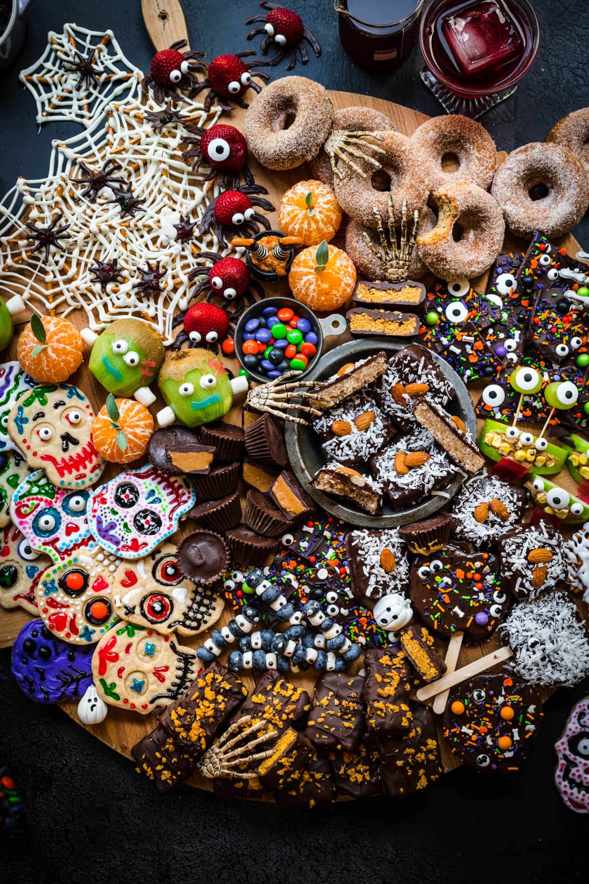 overhead view of halloween dessert charcuterie board with homemade halloween candy, donuts, spooky snacks and more.