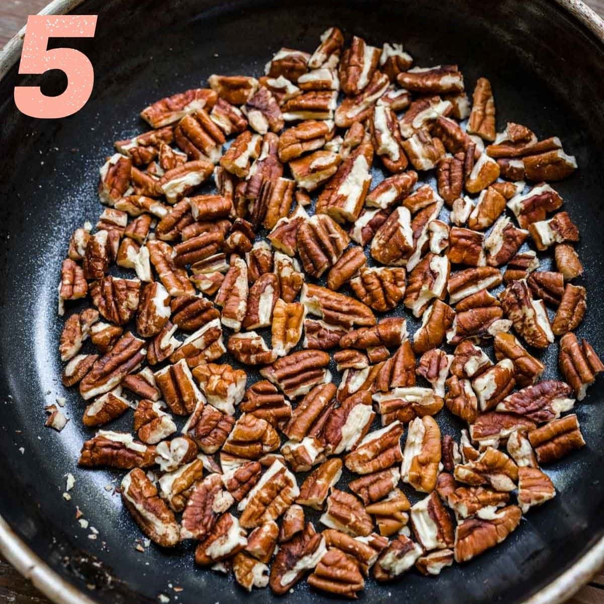 Overhead view of pecans roasting in a pan.