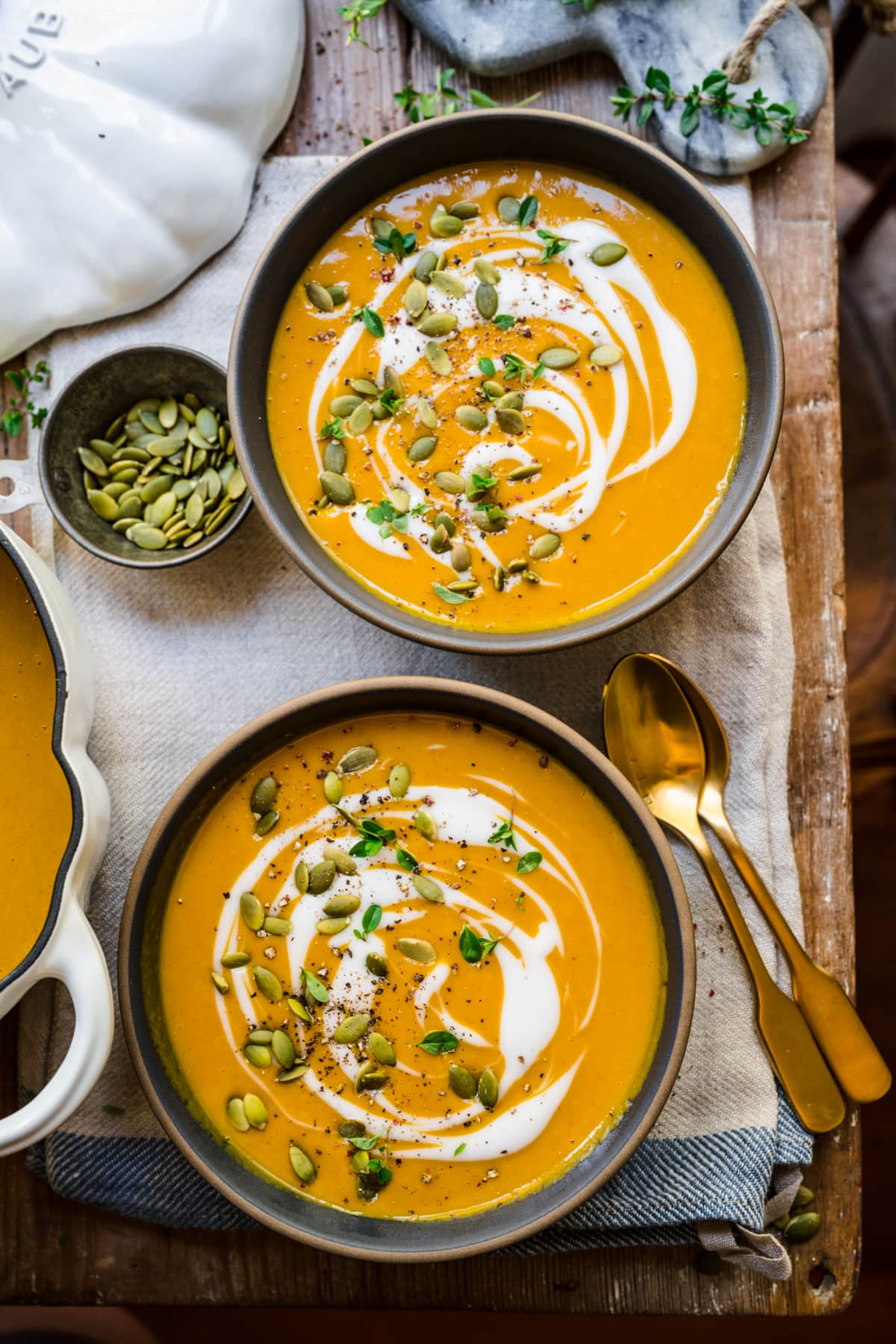 overhead view of two bowls of vegan pumpkin soup on wood table. 