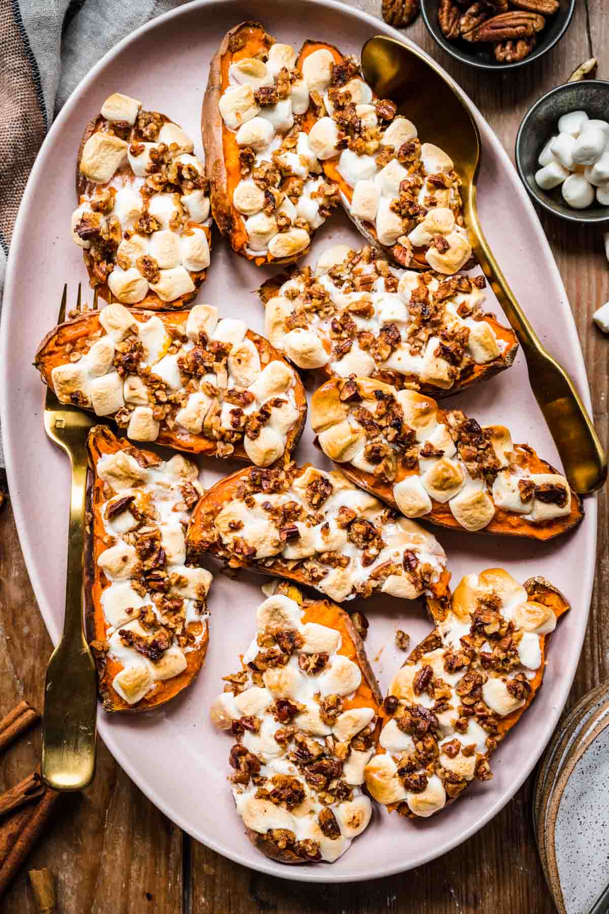 close up view of twice baked sweet potatoes topped with mini marshmallows and pecans on a pink platter.