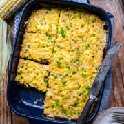 Overhead view of corn casserole in a baking dish topped with cheese and chives.