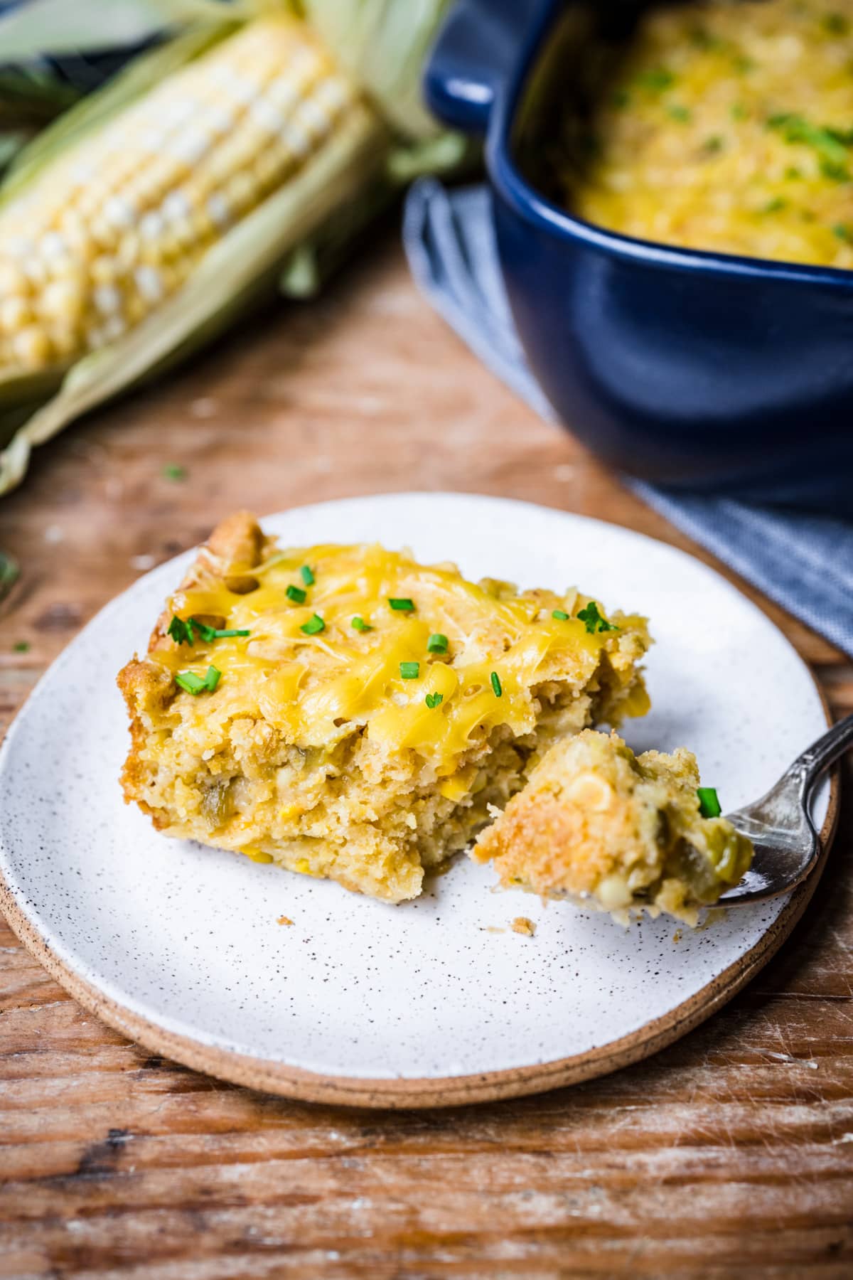 Slice of vegan cornbread topped with cheese on a plate.